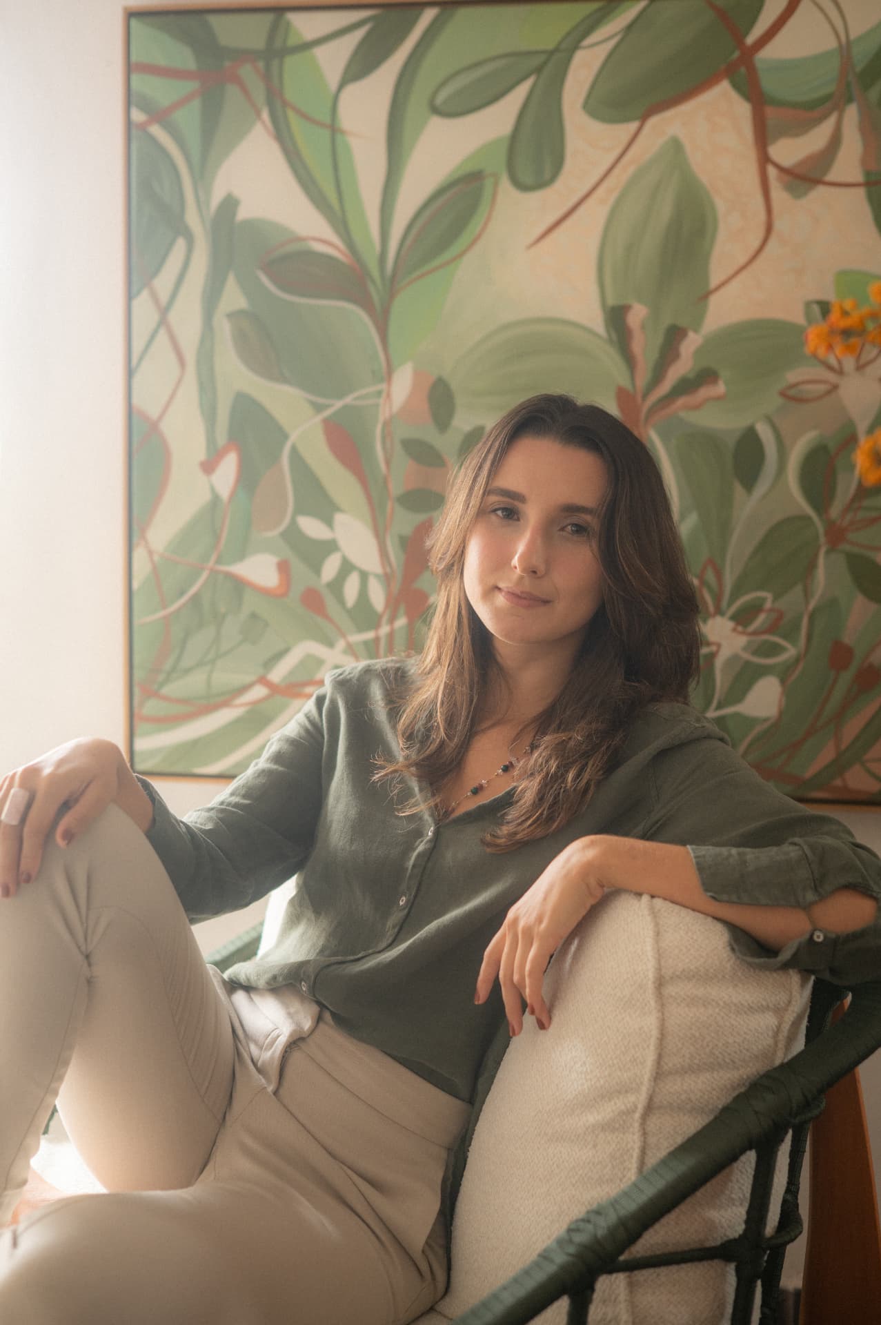Nutricionista sentada em poltrona com quadro botânico ao fundo